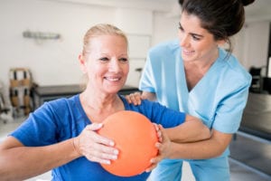 Physiotherapist helping woman in exercise