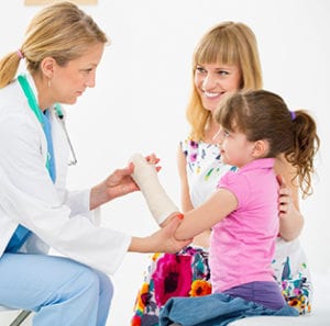 A girl child with her mother at doctor visit for her hand injury