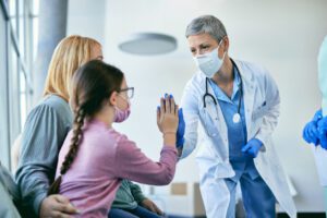 Family Physician giving high-five to small girl