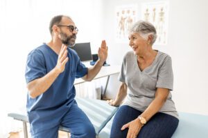Confident mature male chiropractor talks with new patient