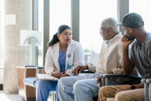 Senior man and his son listen to female doctor at family medical center