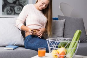 A young woman administering a weight loss injection in her stomach in her living room.